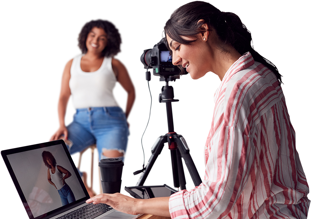 a woman sitting at a desk with a laptop computer besides a camera pointing to a black female model